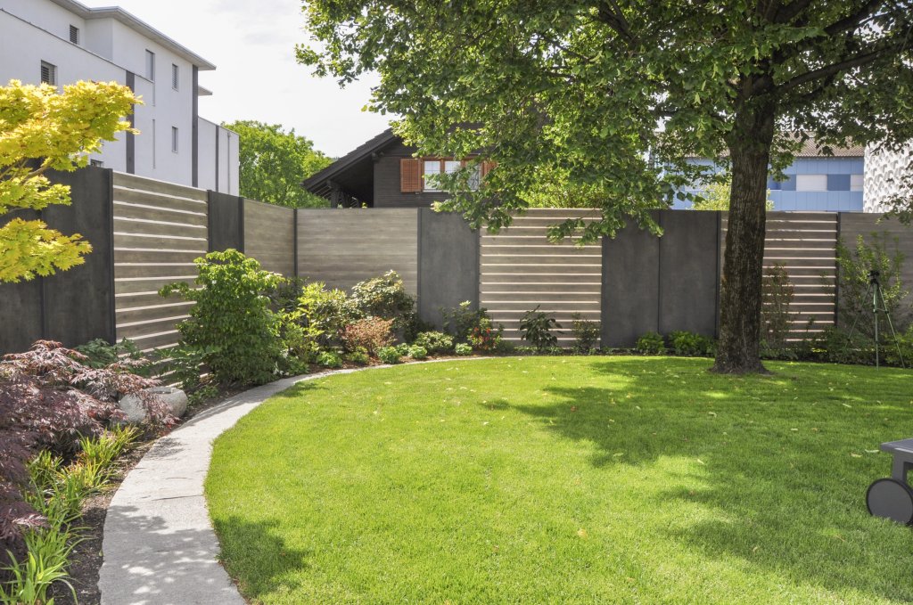 Der Zaun aus Metall und Holz schützt den Garten vor fremden Blicken.