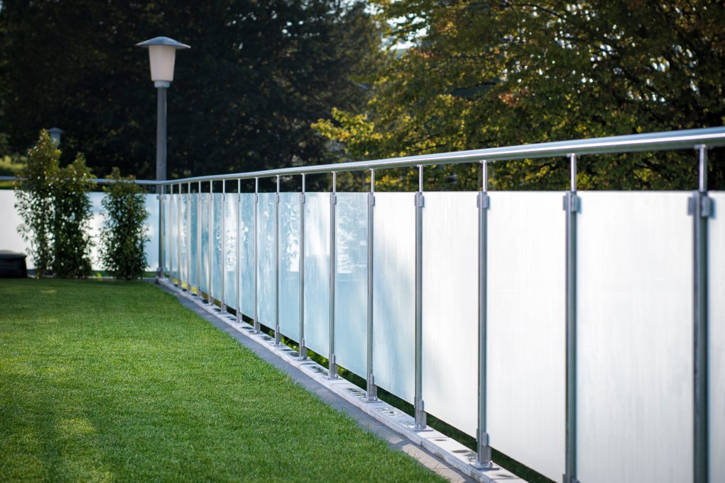 Ein edler Zaun aus Glas und Metall umfasst den grünen Garten und schützt vor neugierigen Blicken. Tore können aus dem selben Material erstellt und verbaut werden.